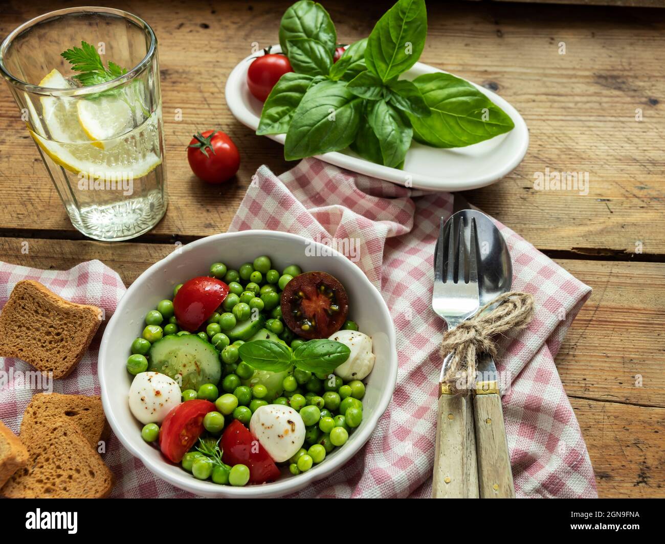 Salad vegetarian. Fresh vegetable salad with tomato, cucumber, basil, green peas, mozzarella cheese. Stock Photo