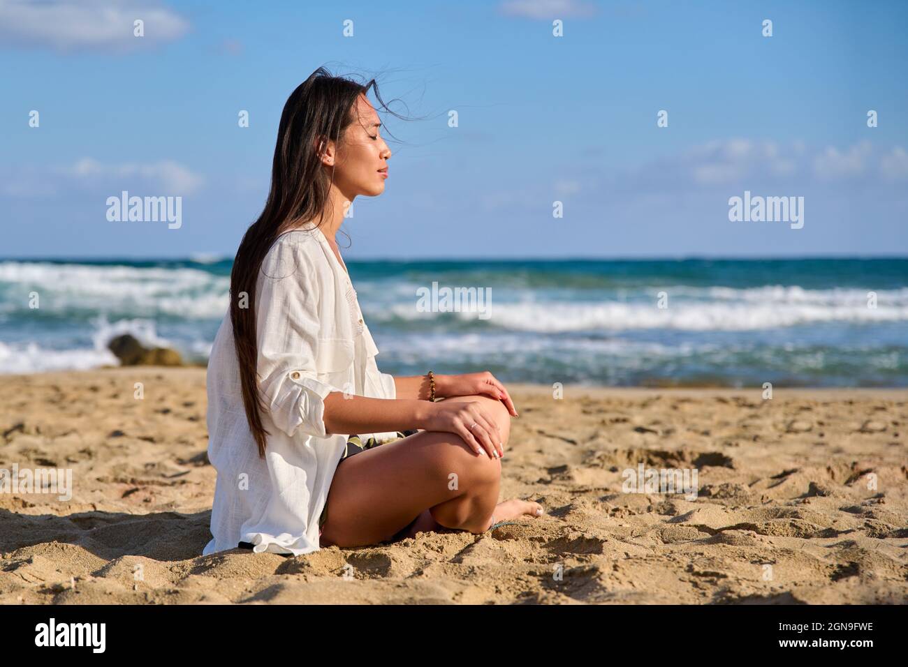 Young beautiful woman in lotus position meditating on the beach Stock Photo