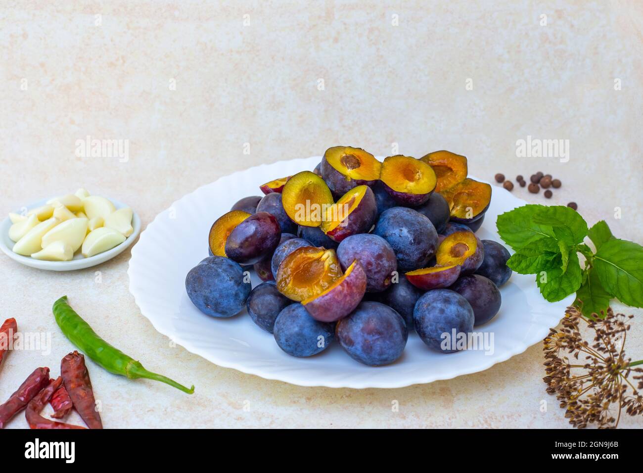 Cooking hot plum sauce. Ingredients for Tkemali on the table - plums, garlic, pepper, mint. Stock Photo