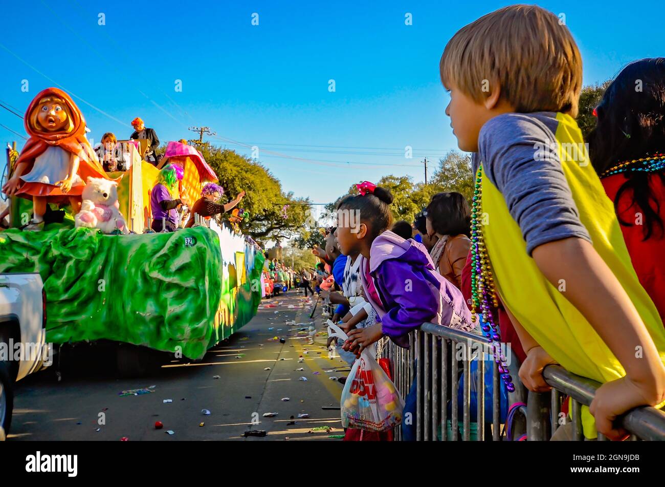 Children watch a Mardi Gras float with a Little Red Riding Hood theme