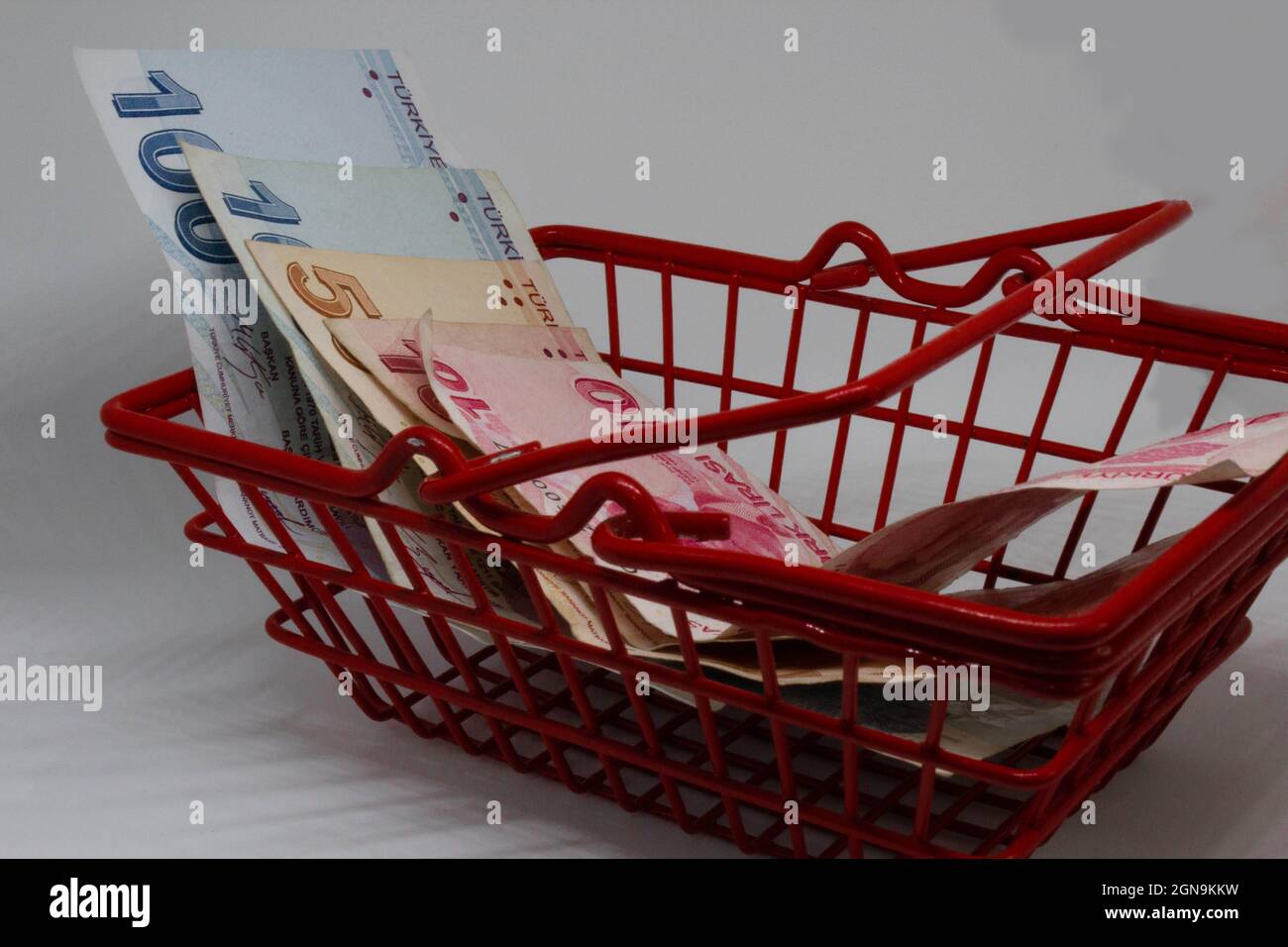 Turkish liras in a red, small shopping basket. Saying that turkish lira has nearly zero purchase power. Low power of money. Bad economy of Turkey. Stock Photo