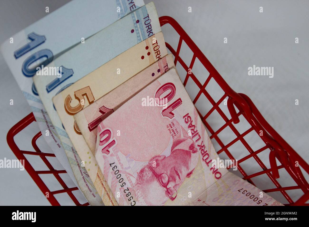 Turkish liras in a red, small shopping basket. Saying that turkish lira has nearly zero purchase power. Low power of money. Bad economy of Turkey. Stock Photo