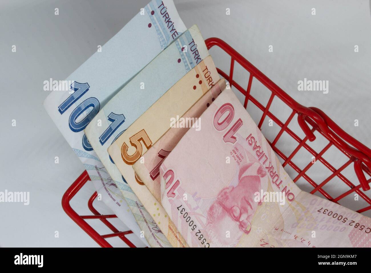 Turkish liras in a red, small shopping basket. Saying that turkish lira has nearly zero purchase power. Low power of money. Bad economy of Turkey. Stock Photo