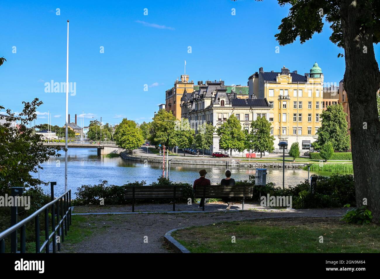 Two unrecognizable persons admire the view of Norrkoping city and Motala river at Refvens grund on a sunny day in August. Stock Photo