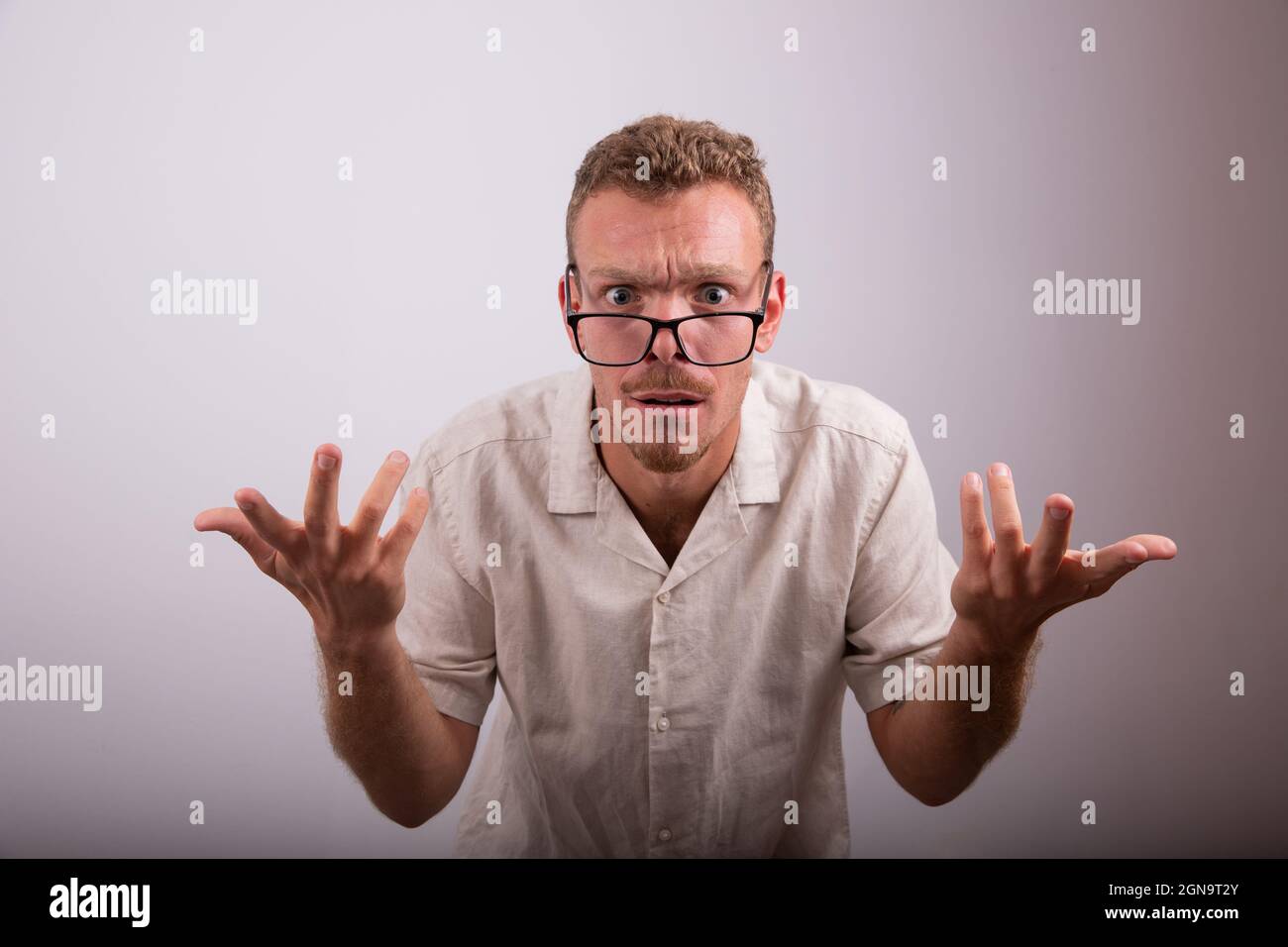 Man with surprised expression, guy with astonished face and raised arms. Nerd person with eyeglasses, millennial person Stock Photo