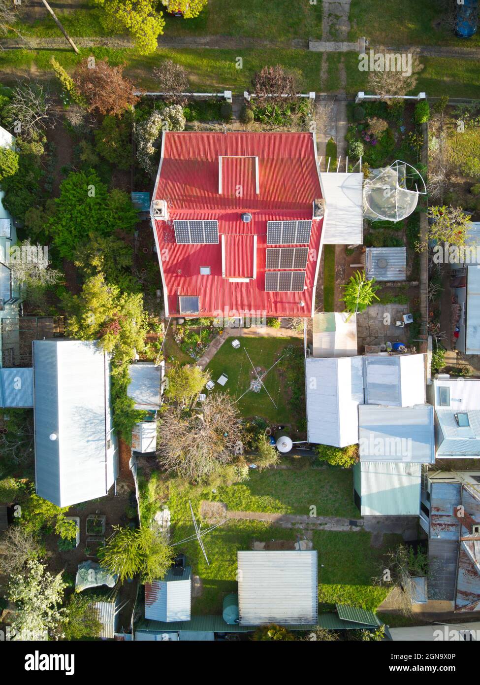 Aerial view house solar panels, red roof, sheds and garden in