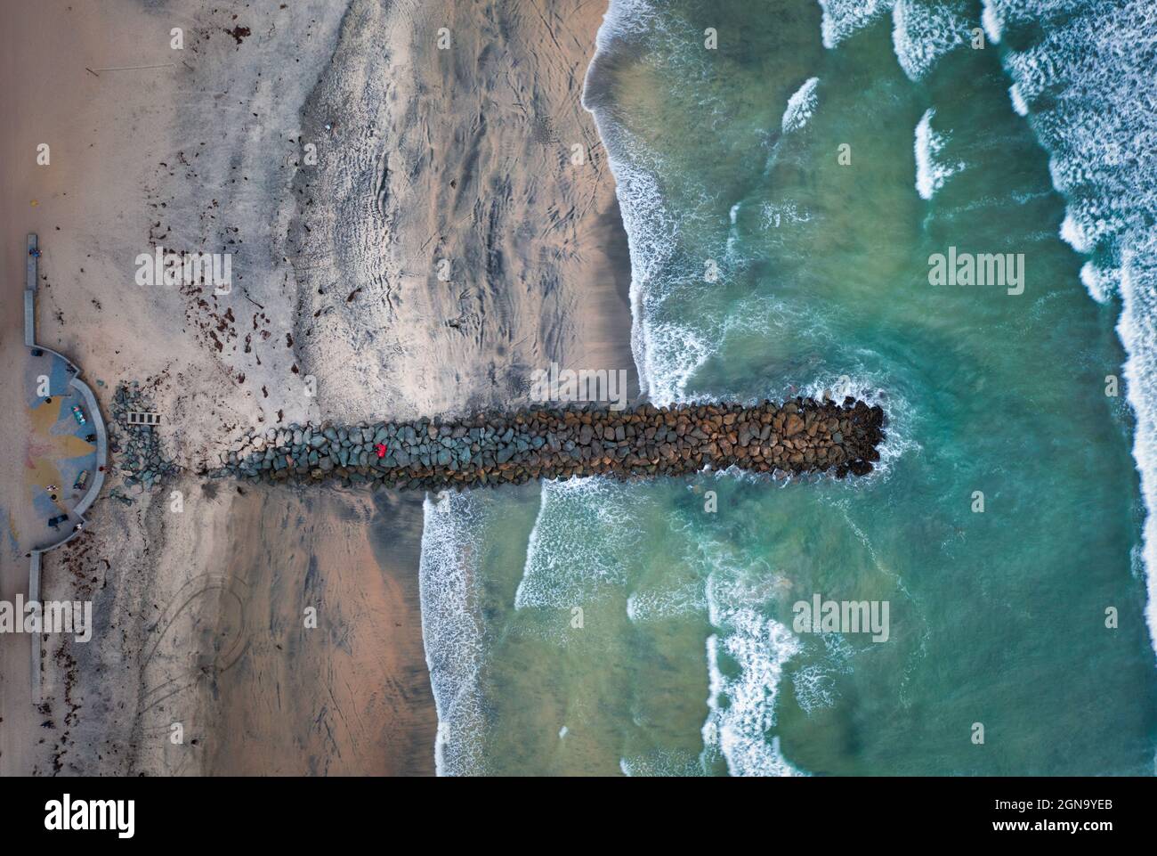 Overhead top-down drone view of jetty with waves breaking Stock Photo