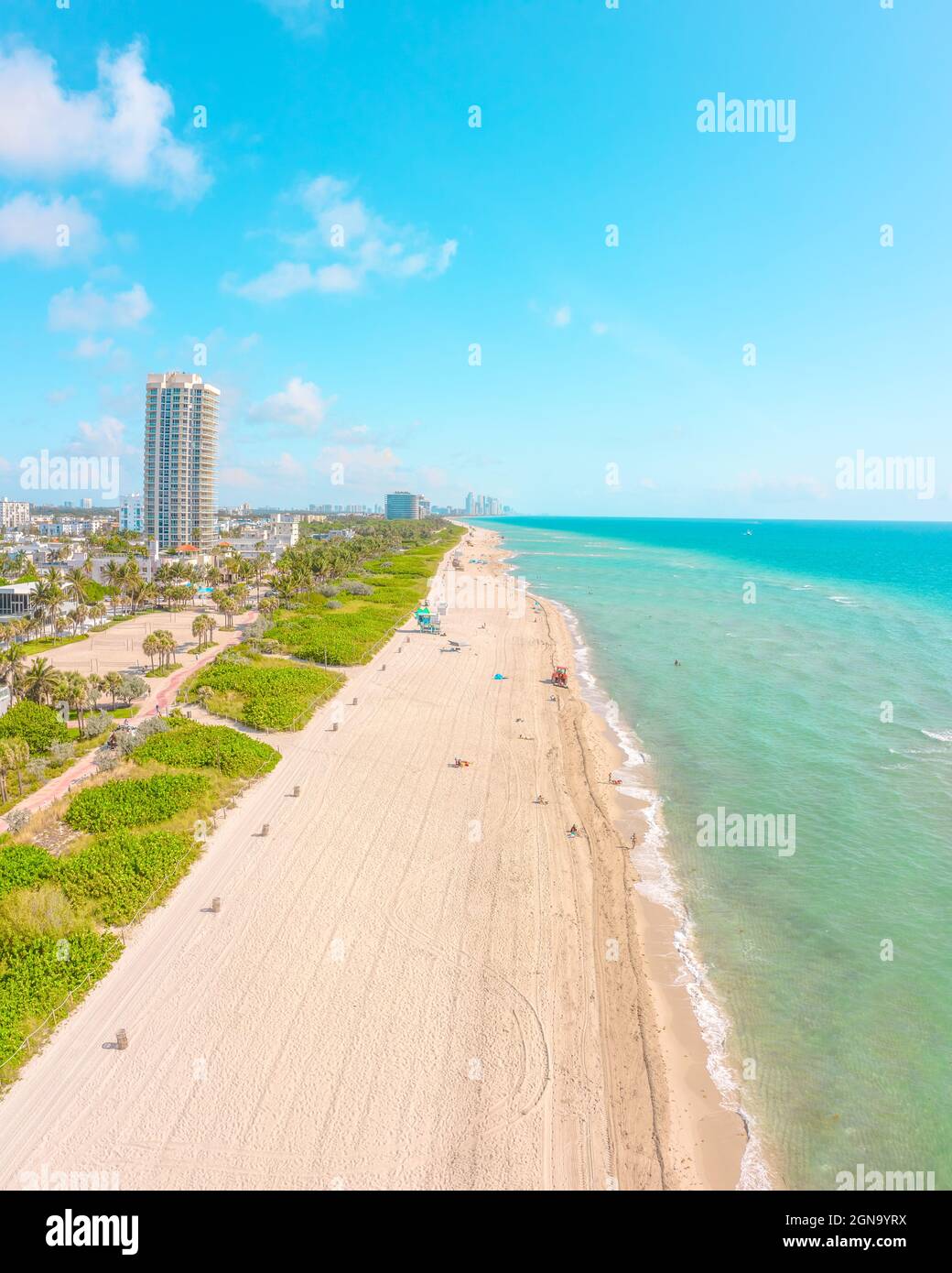 Beautiful Miami Beach on a sunny morning with white sandy beach, blue water, and greenery behind beach Stock Photo