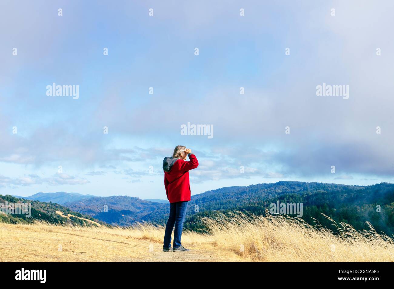 Woman in red jacket looking out at California Coastal Range Stock Photo