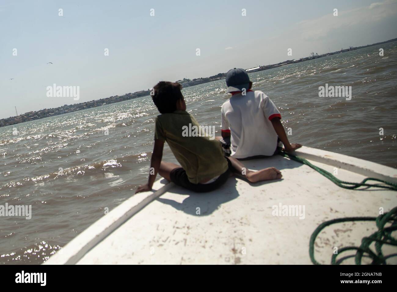 two poor children riding the front of a fishing boat third world country poverty Stock Photo