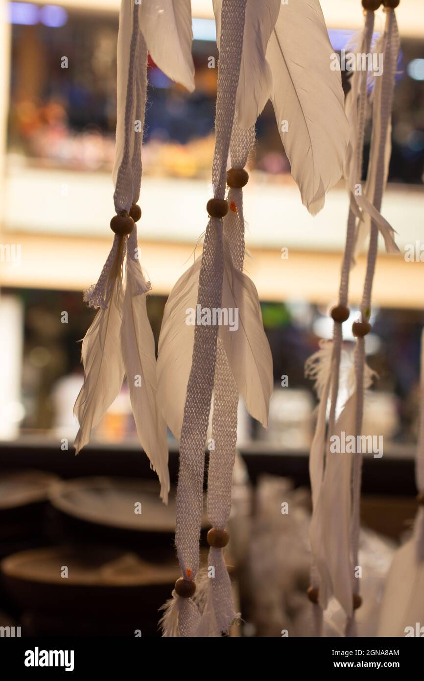 Closeup shot of long white feathers hanging in the indoor market in ...