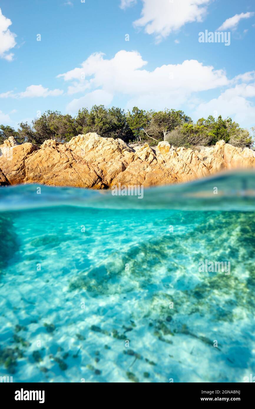 Split shot, over under photo. Half underwater with turquoise water and a rocky coast on the water surface. Prince Beach (Spiaggia del Principe) Stock Photo