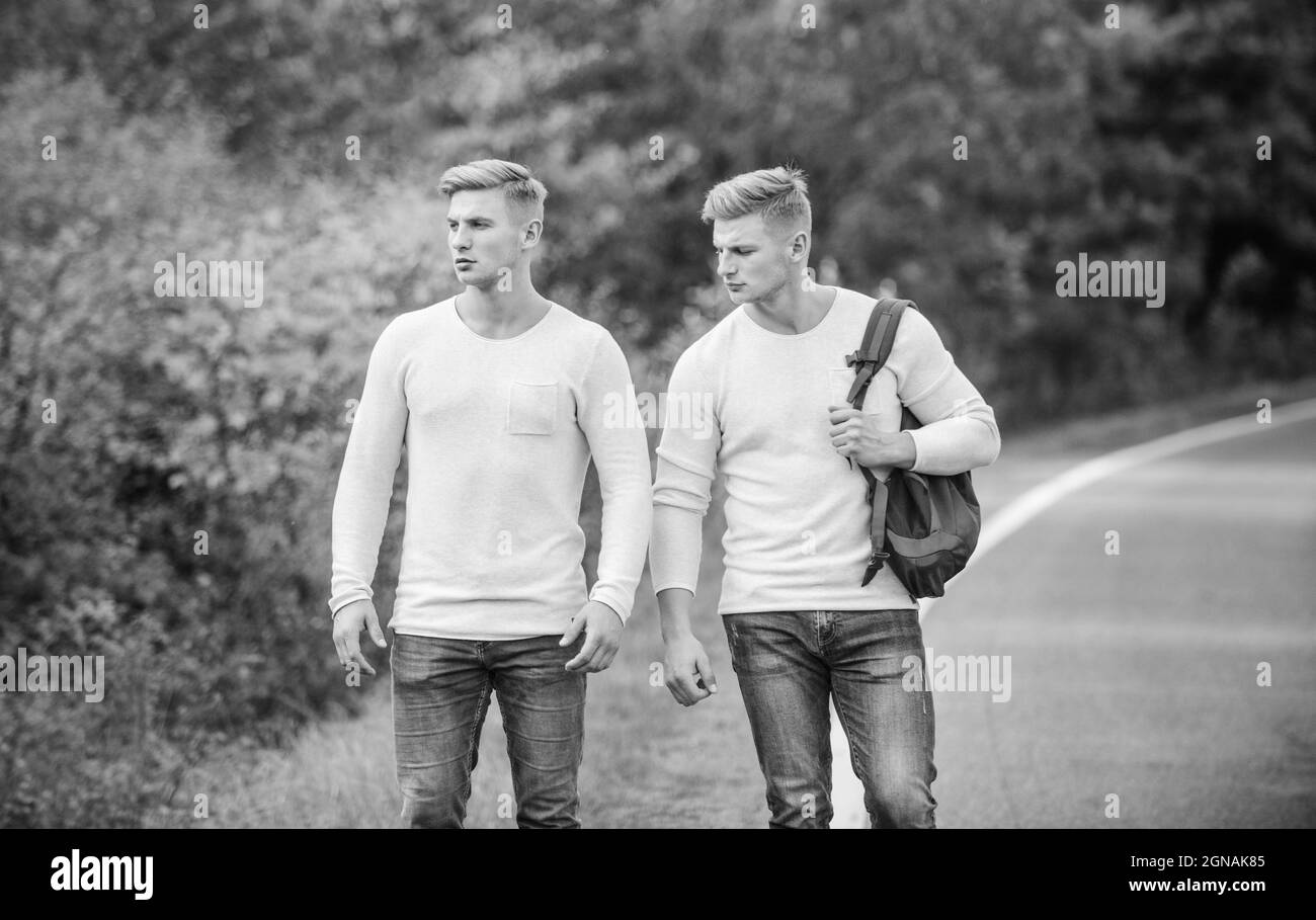 two brothers go adventure. friendship concept. men hitch hiking. man casual style travel with backpack. traveler hitchhiking on highway. on the way Stock Photo