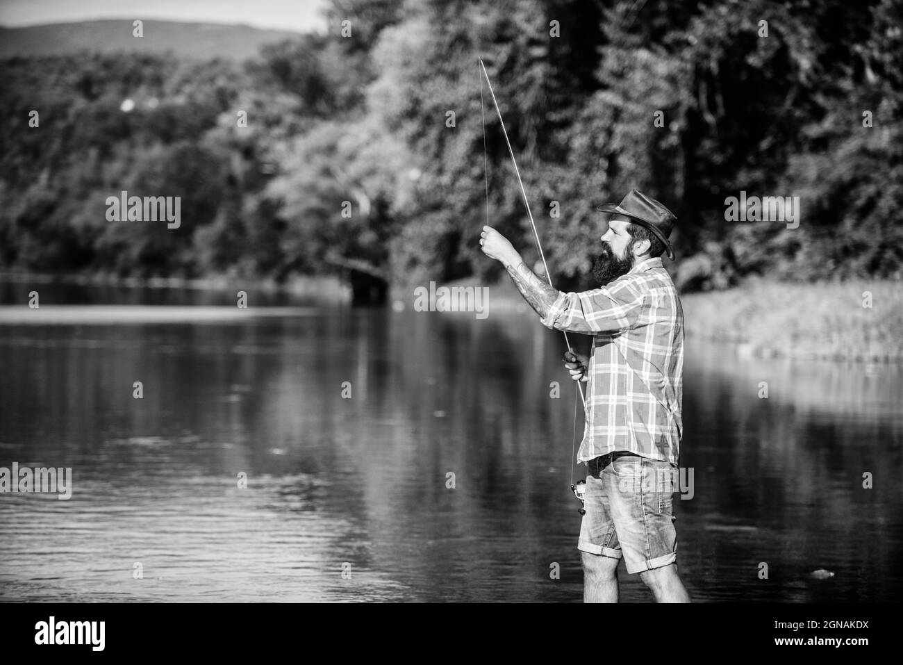 What a fish. mature bearded man with fish on rod. big game fishing. relax on nature. hipster fishing with spoon-bait. successful fisherman in lake Stock Photo
