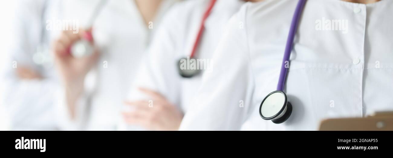 Team of doctor in white coats and stethoscopes stand together Stock Photo