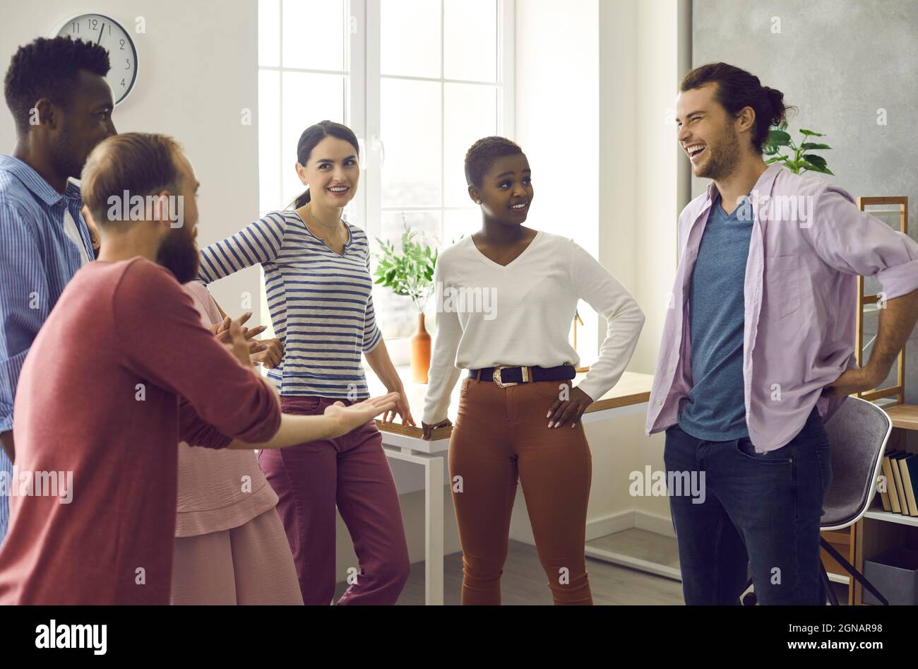 Company of cheerful young multinational friends communicate by telling funny stories. Stock Photo