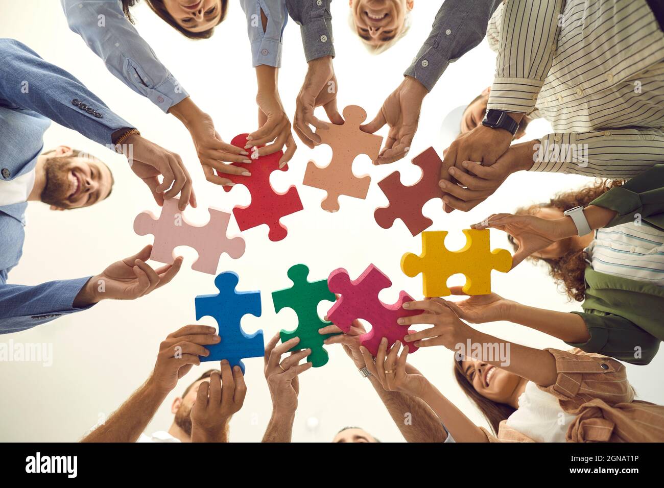 Shot from below of team of happy business people connecting pieces of