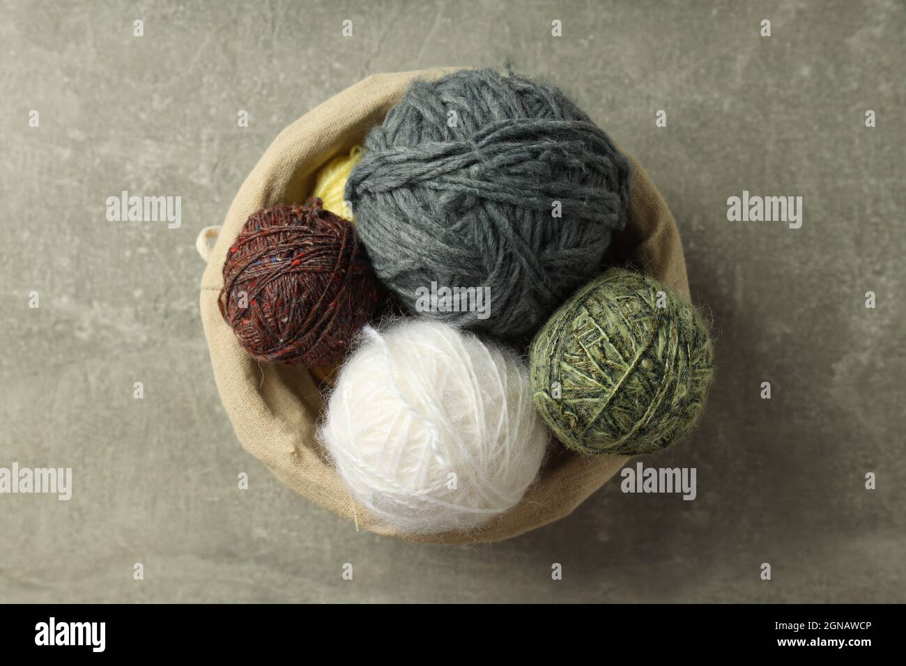 Wicker basket with yarn balls on light gray table Stock Photo