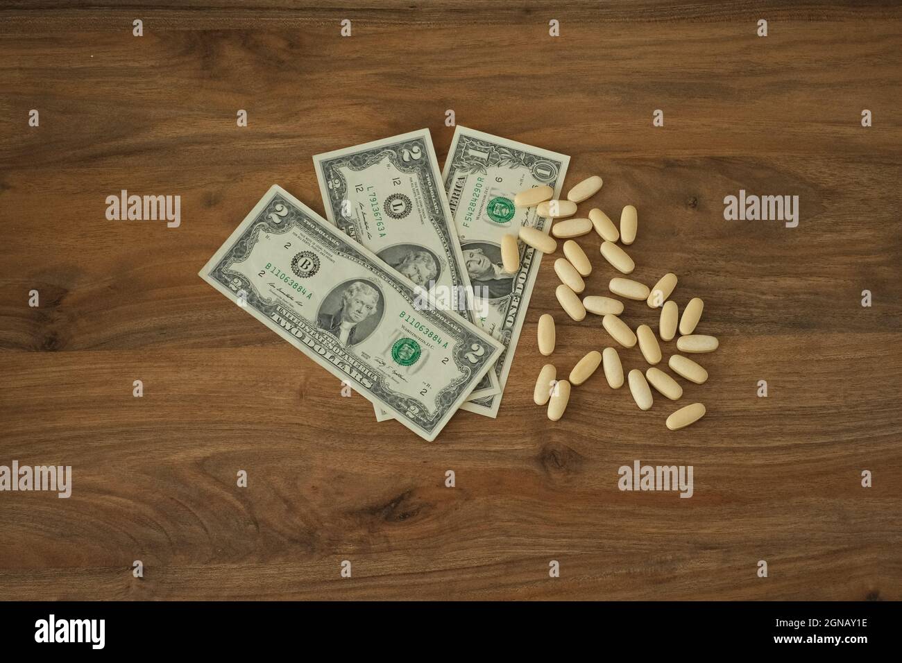 Money and pills on the wooden table top view. Paid medicine idea concept. Financial distress and thinking about suicide. Stock Photo