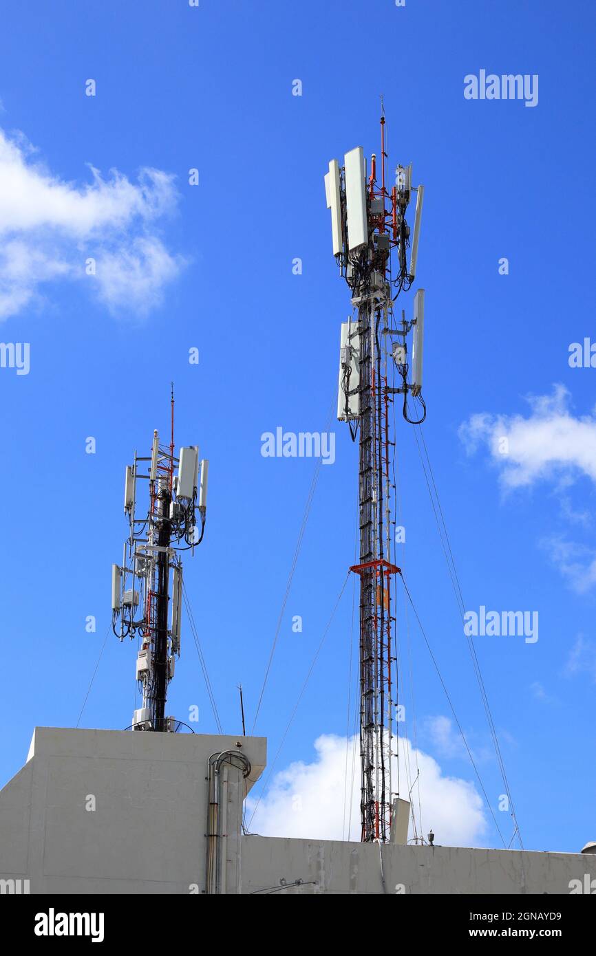 Wireless Communication Antenna pole, Mobile phone mast antenna pole on top of dilapidated building Stock Photo