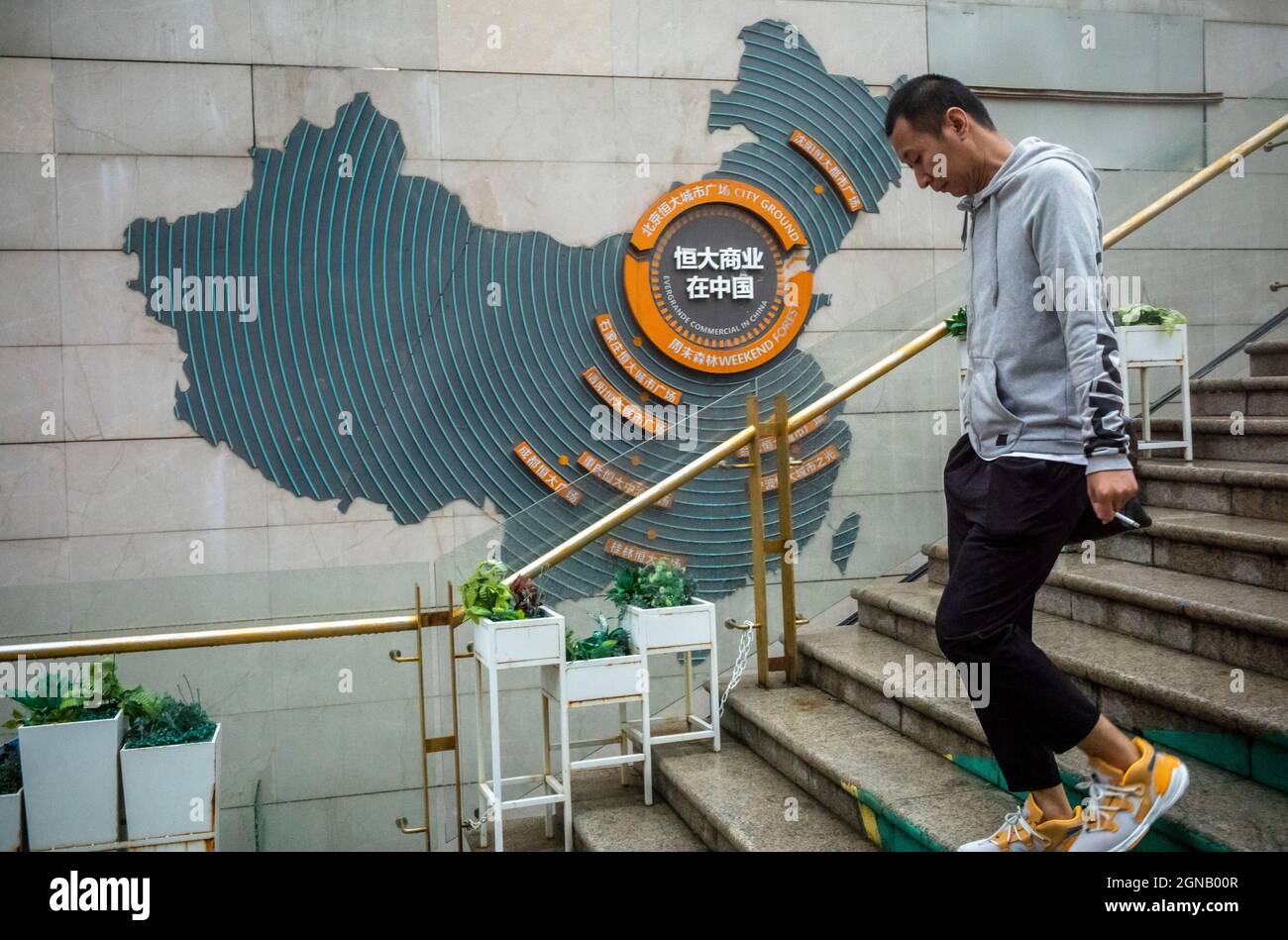 A man walks by a logo and map of China with Evergrande hubs at Evergrande city plaza in Beijing, China on 24/09/2021 Real Estate corporate financial troubles affect stock markets . Evergrande's shares were trading almost 10% lower in Hong Kong on Friday after jumping more than 17% the previous day. by Wiktor Dabkowski Stock Photo