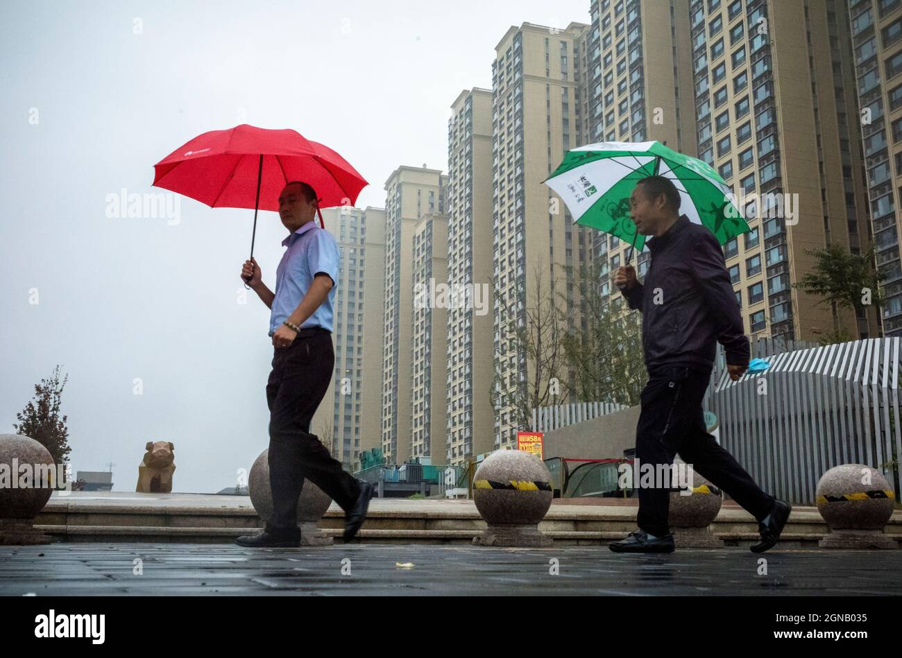 Pedestrians with umbrellas walks by Evergrande Royal Scenery housing complex in Beijing, China on 24/09/2021 Real Estate corporate financial troubles affect stock markets . Evergrande's shares were trading almost 10% lower in Hong Kong on Friday after jumping more than 17% the previous day. by Wiktor Dabkowski Stock Photo