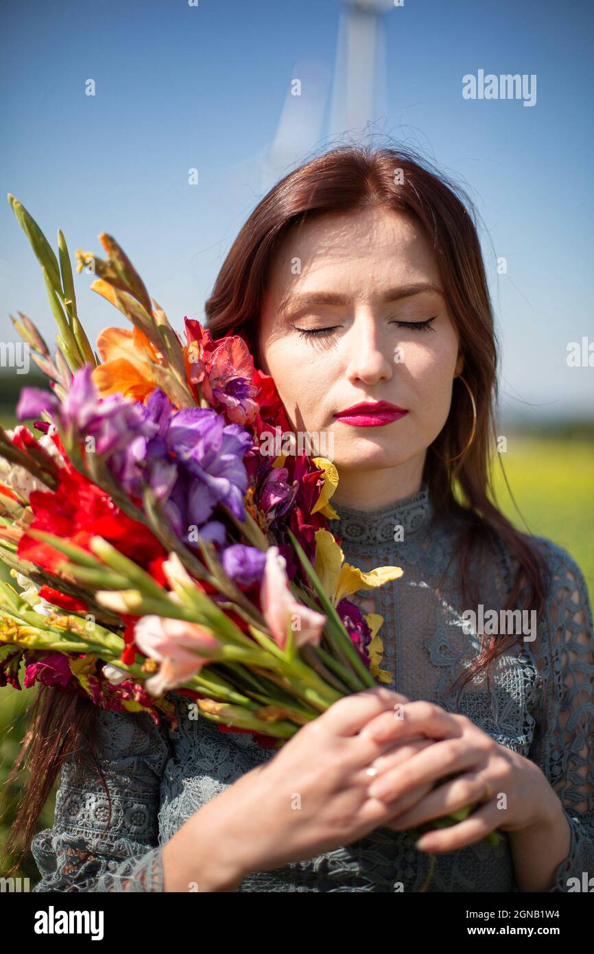 White young girl with dark hair with sky behind with bright flowers ...