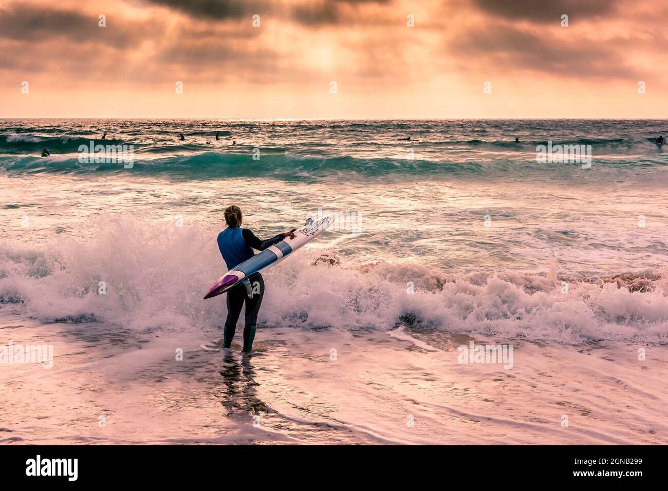 Late evening light over a member of Newquay Surf Lifesaving Club at a training session on Fistral Beach in Newquay in Cornwall. Stock Photo
