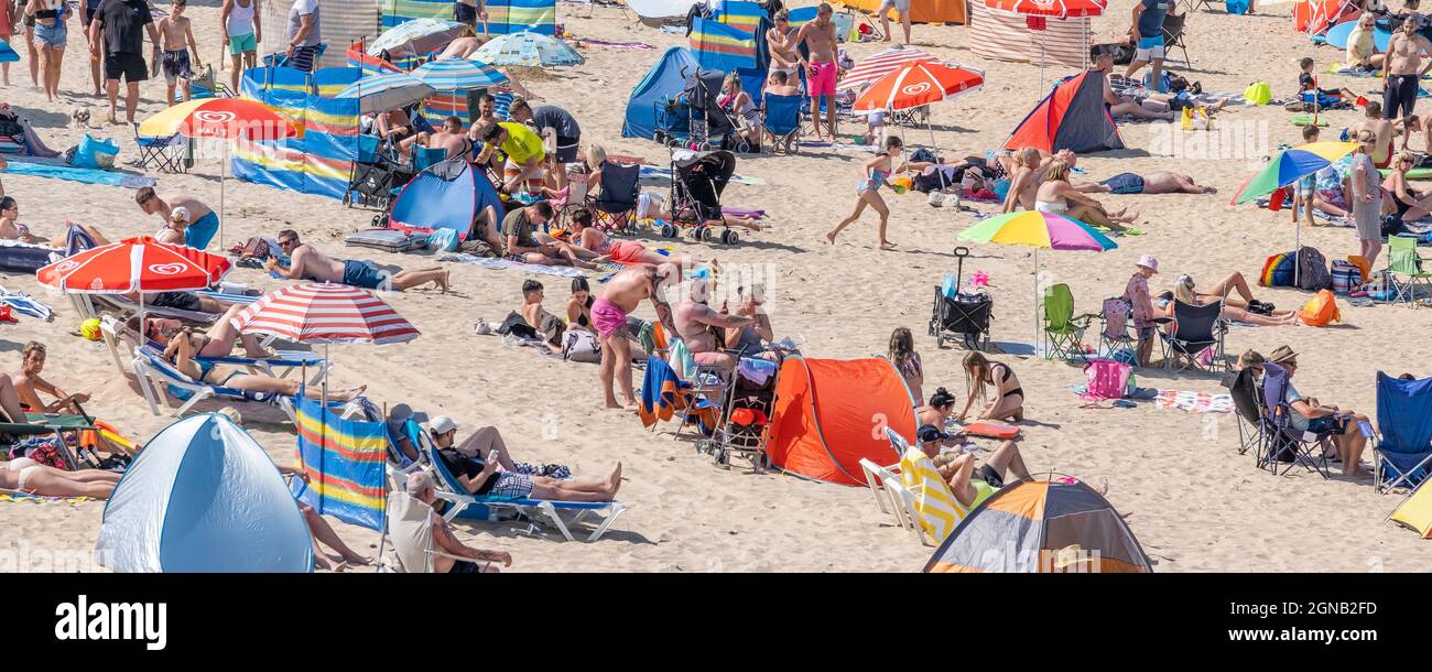 A panoramic image of intense heat and non-stop sunshine bringing out the crowds of holidaymakers onto Fistral Beach in Newquay in Cornwall. Stock Photo