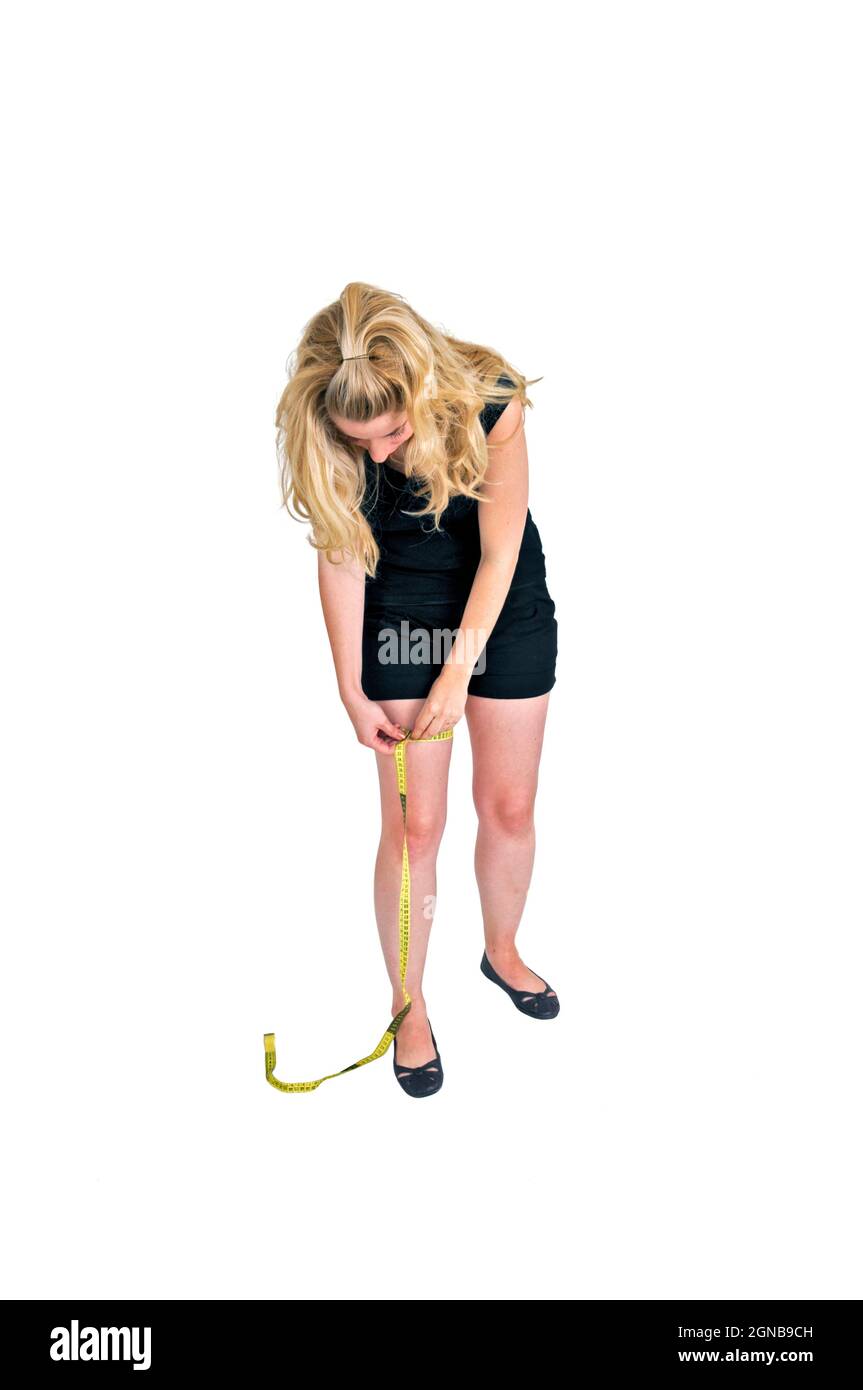 Body image - young woman measures her leg Stock Photo