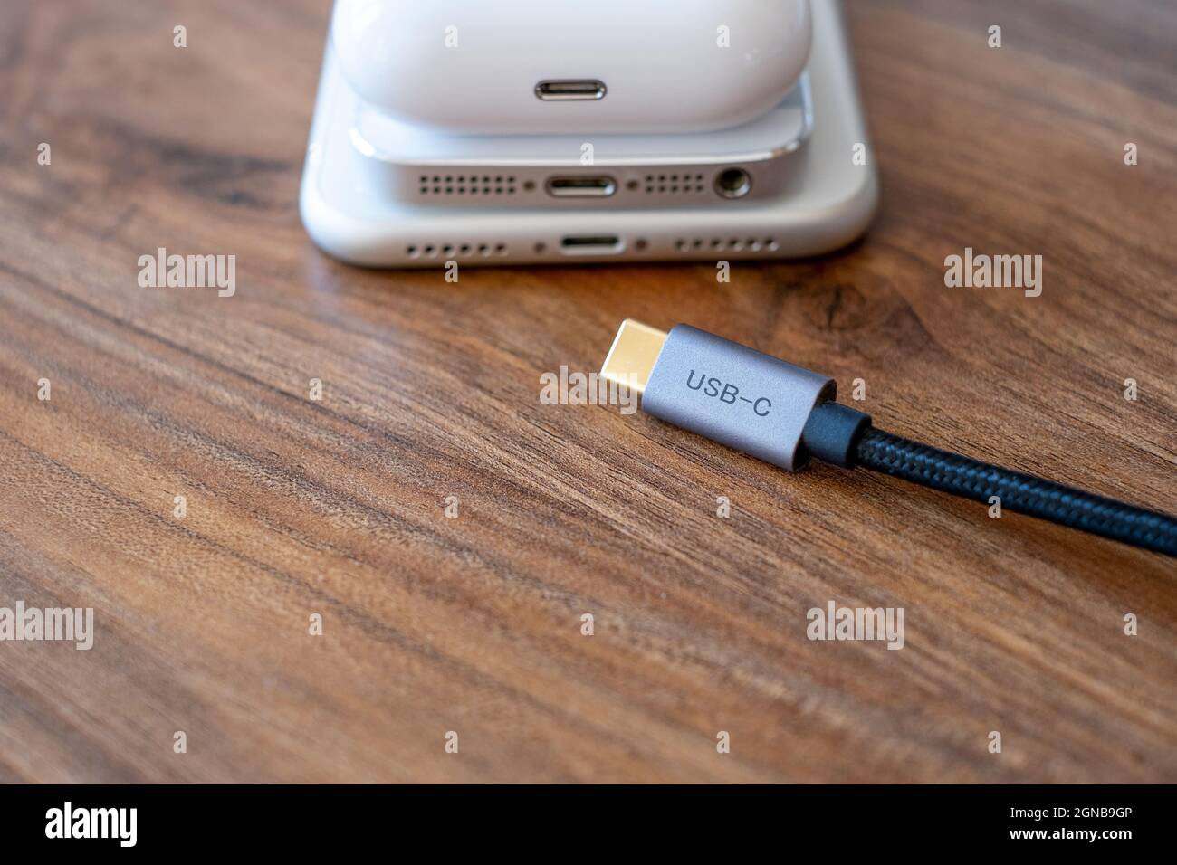 Trying to put type-c  or usb-c on mobile phone. Smartphones headphones and type c cable on the table Stock Photo