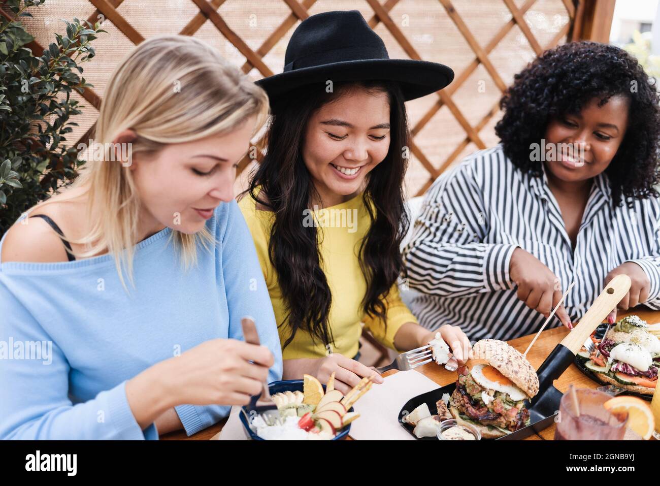 Young multiracial friends having breakfast outdoors in restaurant - Focus in asian girl face Stock Photo