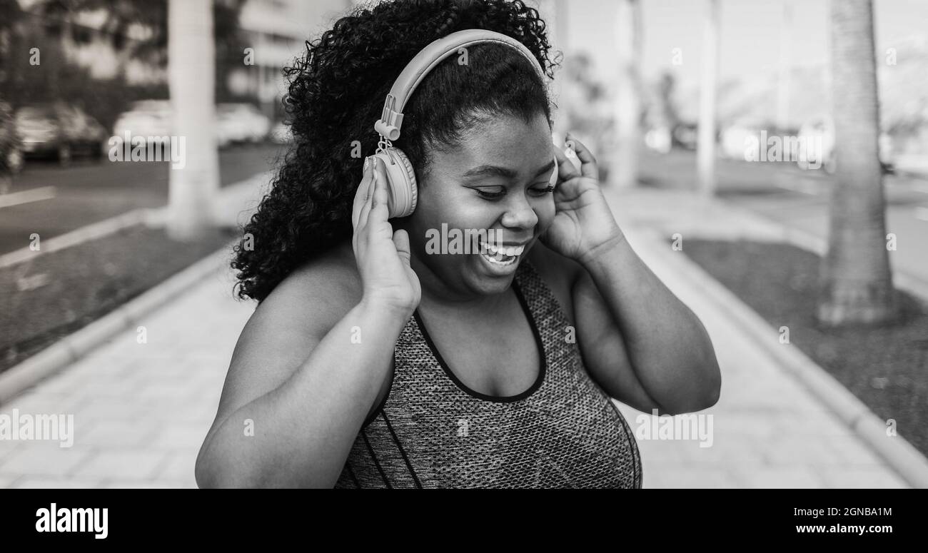 Curvy woman dancing and listening music with headphones while jogging