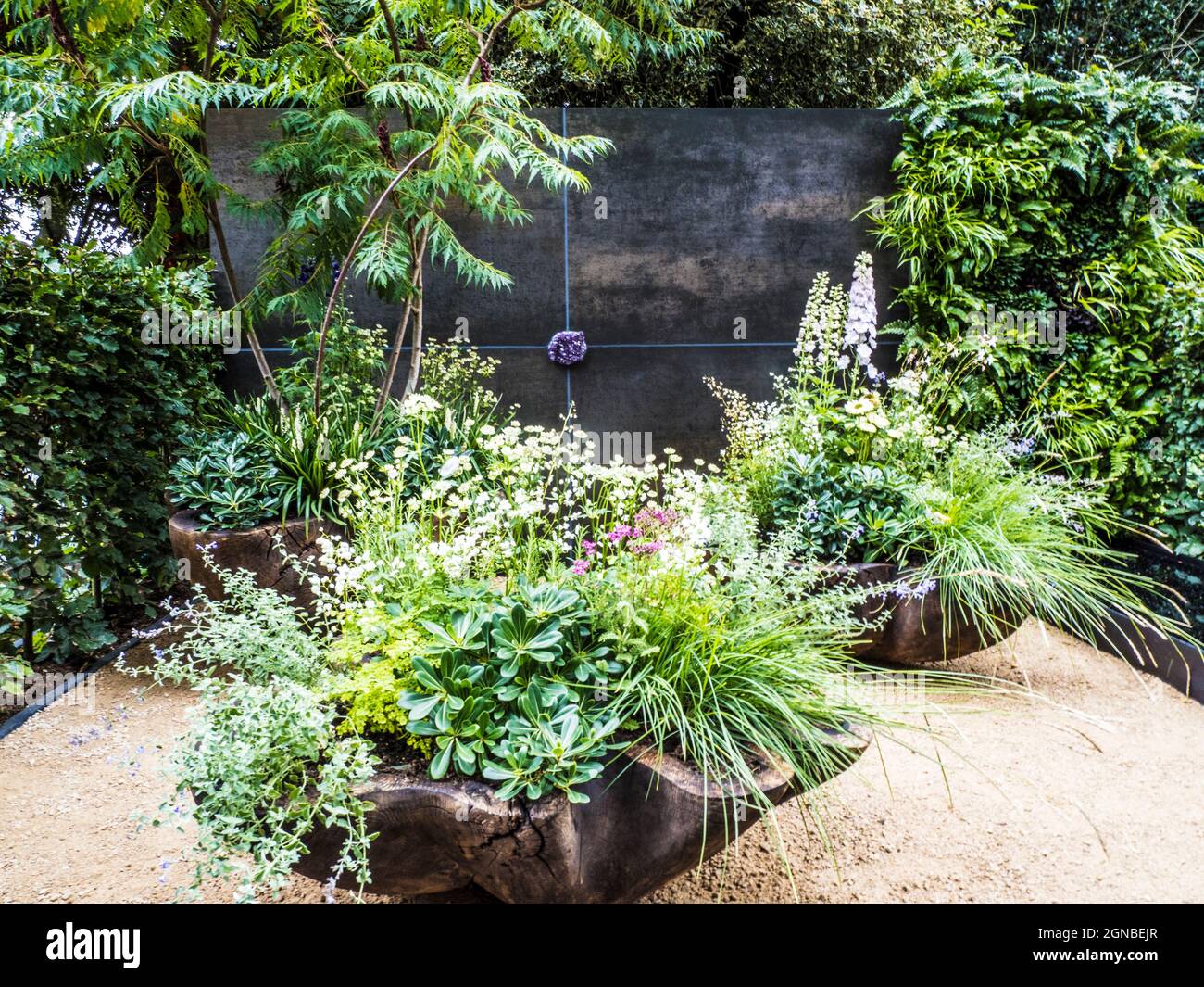 A gravel patio with chair and richly planted containers. Stock Photo