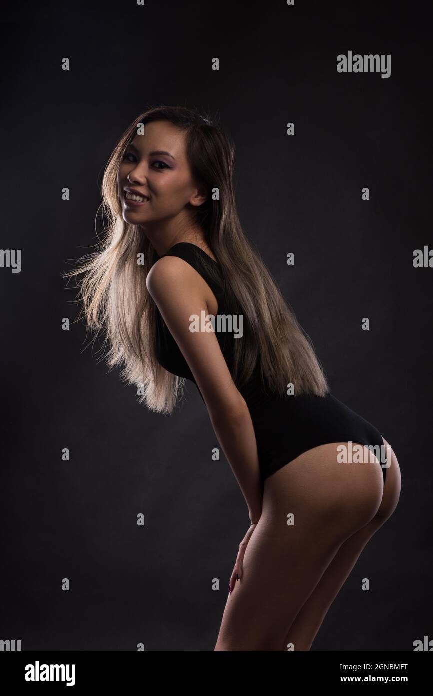 Young slim asian woman in black bodysuit posing at studio Stock Photo