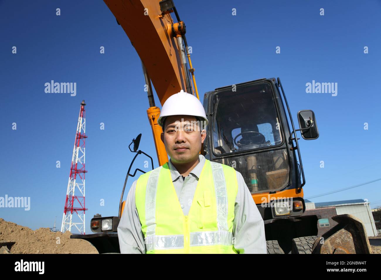 portrait construction worker on location site standing beside excavator ...