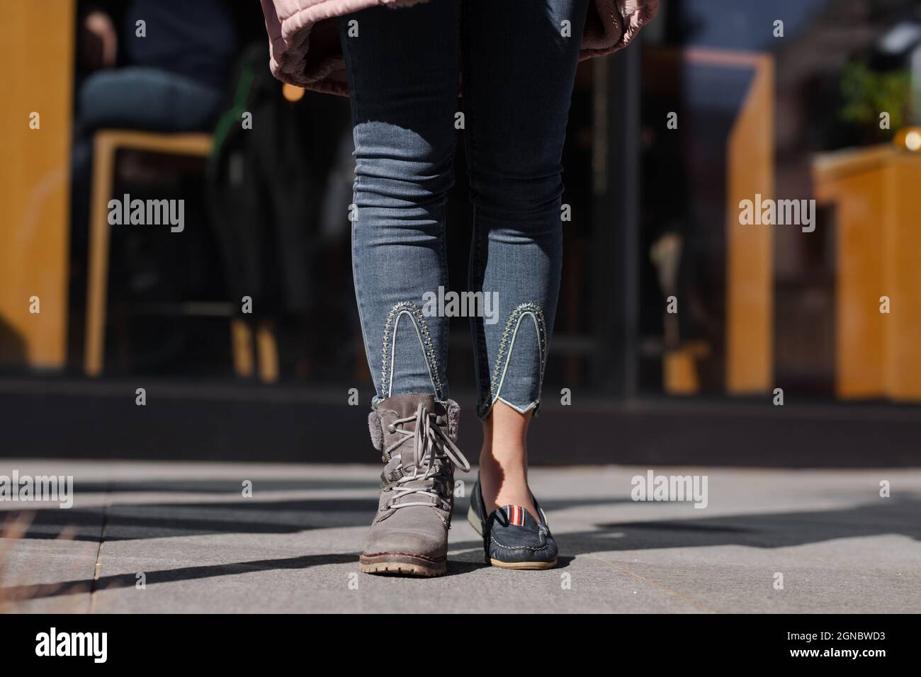 Girl wearing different shoes on her feet. Boots and sandals. Outdoor shot  on a street Stock Photo - Alamy