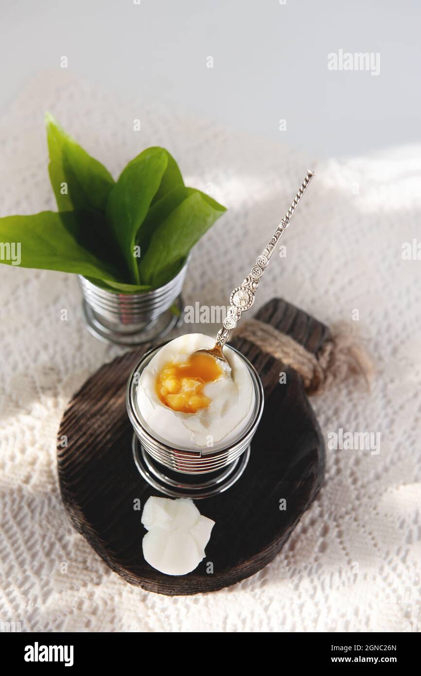 Open a soft-boiled egg in an egg cup. Homemade low-calorie breakfast on a rustic table. copy space Stock Photo