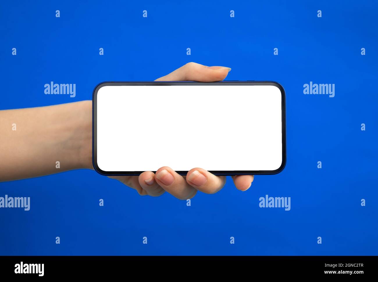 Hand with mobile phone mockup screen horizontally on a blue background ...