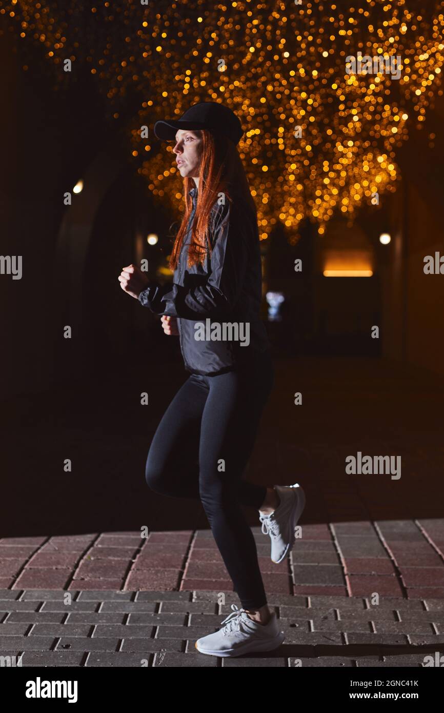 Side view of athlete woman in black wear running at night. female