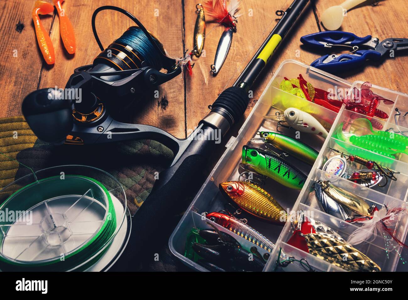 fishing tackle - spinning rod with box of lures and angling equipment on wooden table Stock Photo