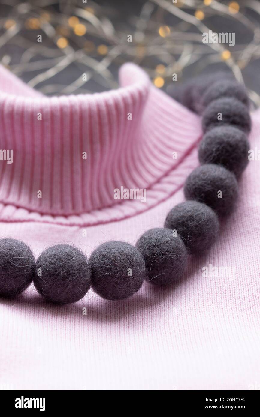 Handmade wool necklace on the background of clothes. Stock Photo