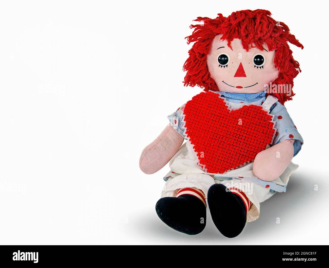 Old rag doll with red yarn heart isolated on white Stock Photo