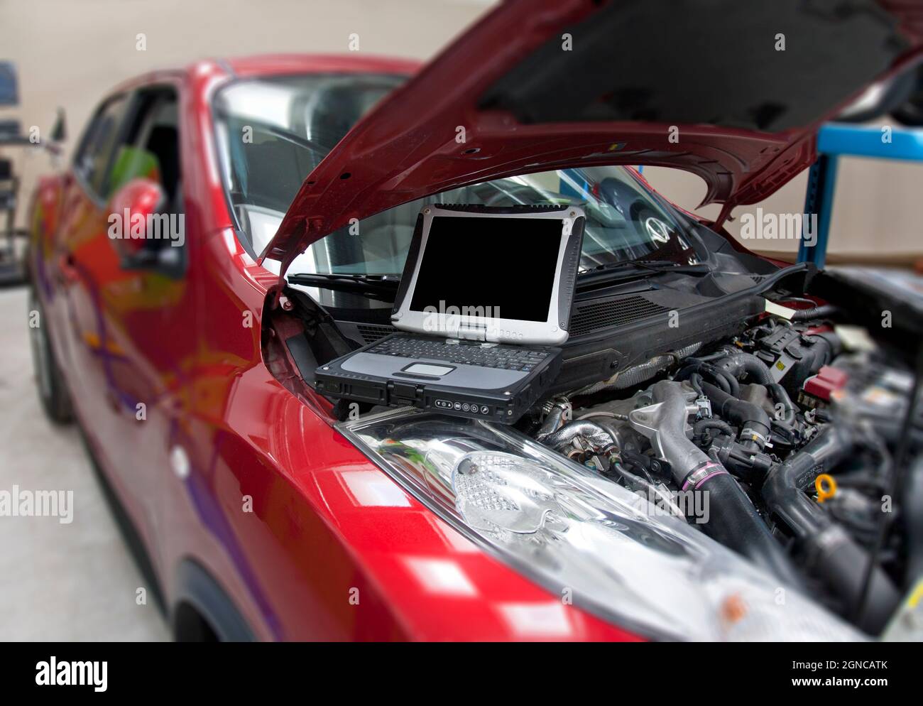 Car in a workshop and a computer running diagnostics on the engine ...