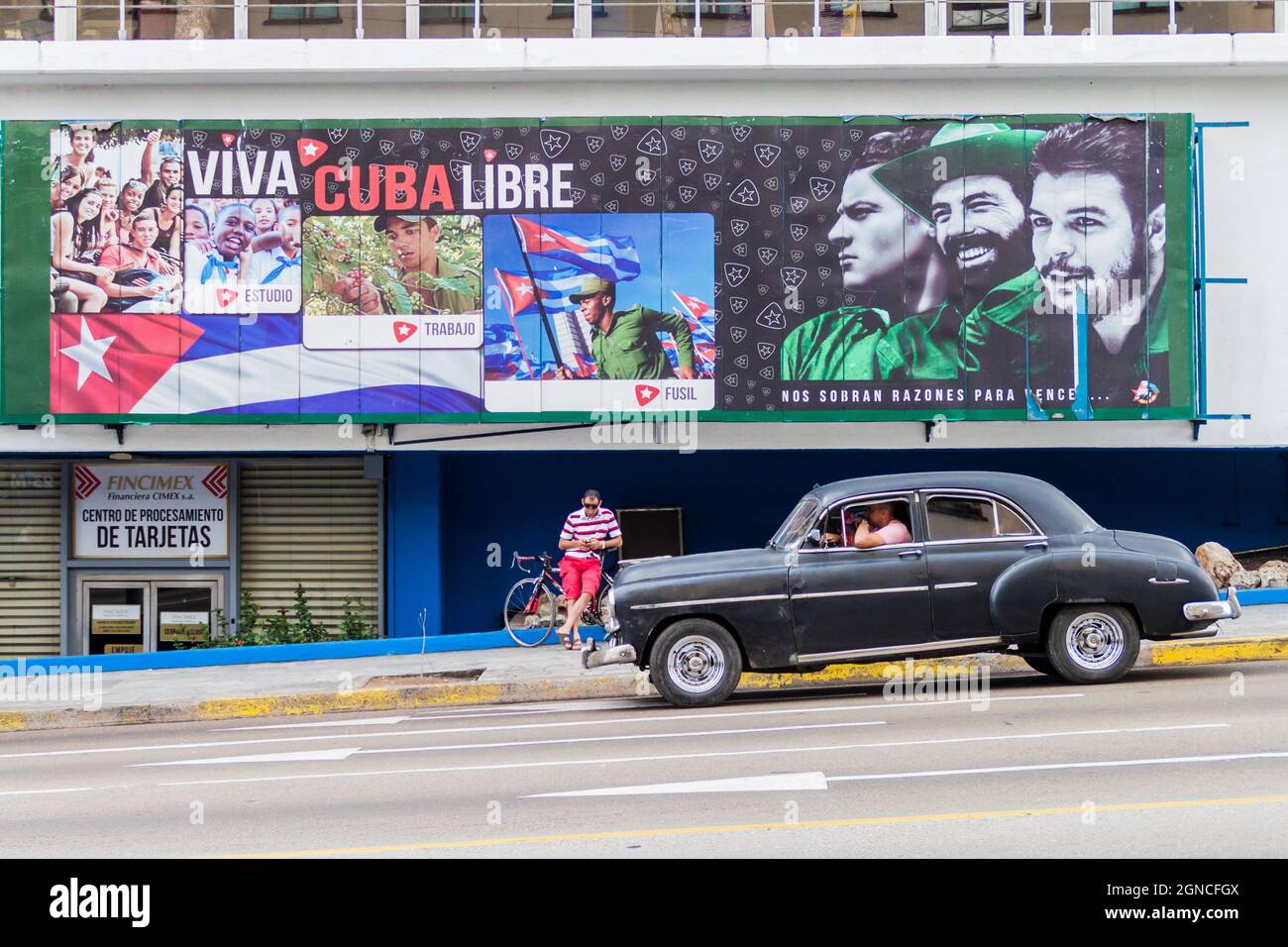 HAVANA, CUBA - FEB 21, 2016: Vintage car and a propagandistic poster in Vedado neighborhood of Havana. Stock Photo