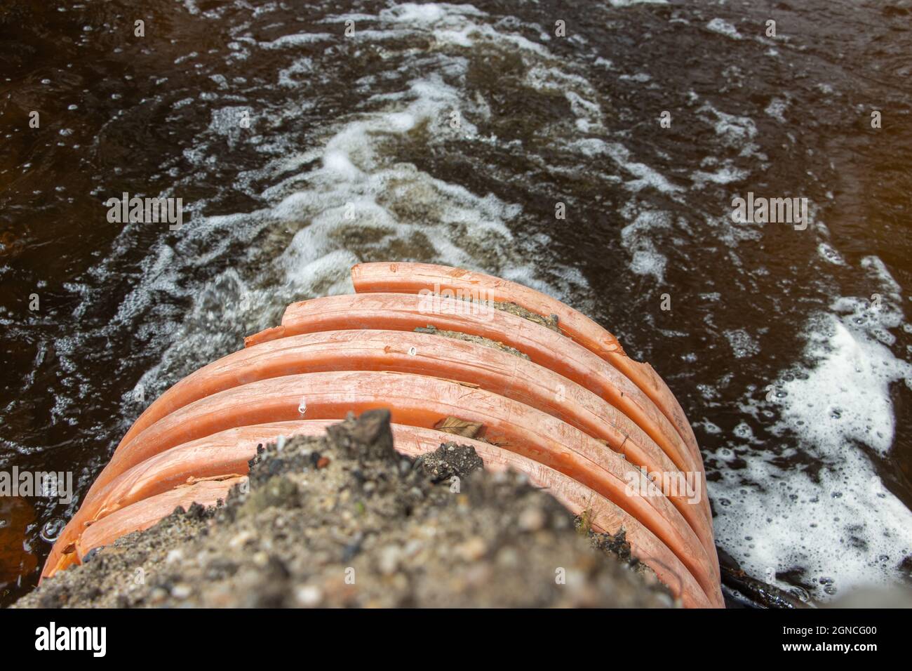 A stream of water flows from a large flexible pipe - hose. Stock Photo