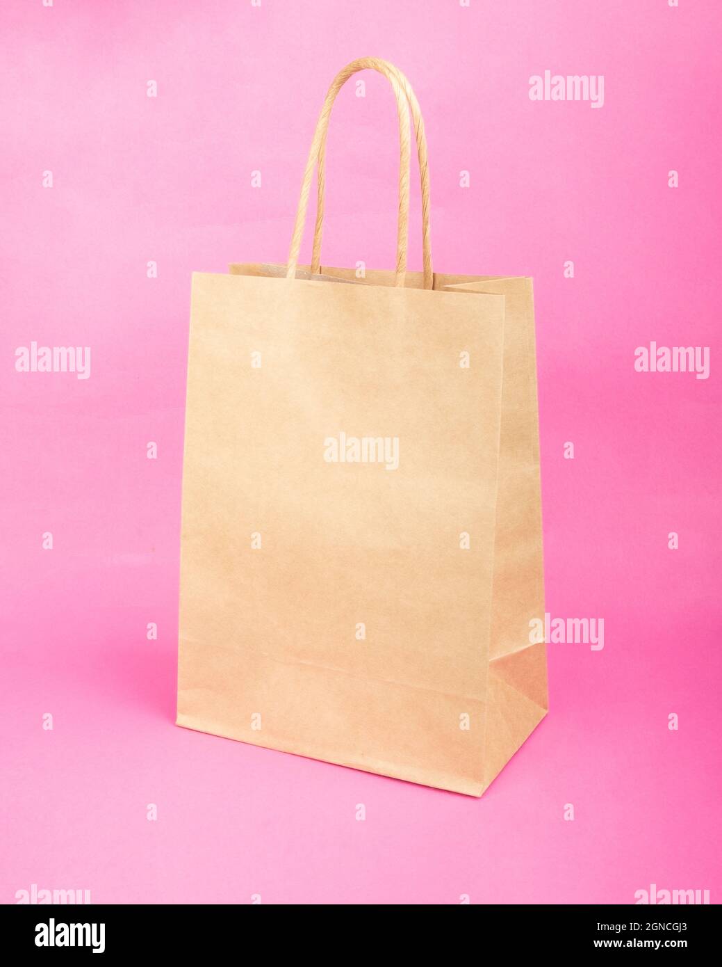 empty paper bag with copy space for lettering, sale mockup on pink background. Stock Photo