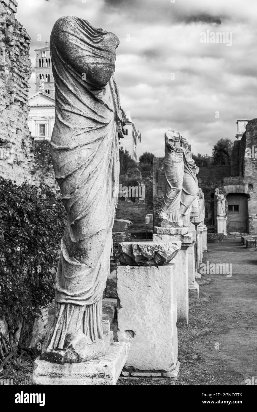 Black and white photo of line of ancient marble statues in ruins