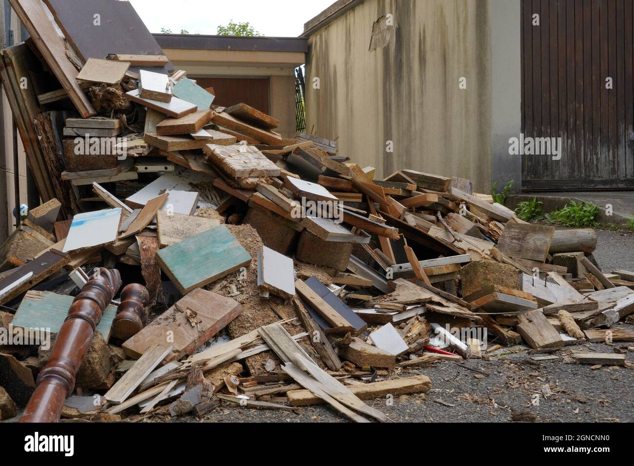 Dismantled furniture on a yard between two buildings. There are pieces of wooden furniture piled up. They are of irregular size. Stock Photo