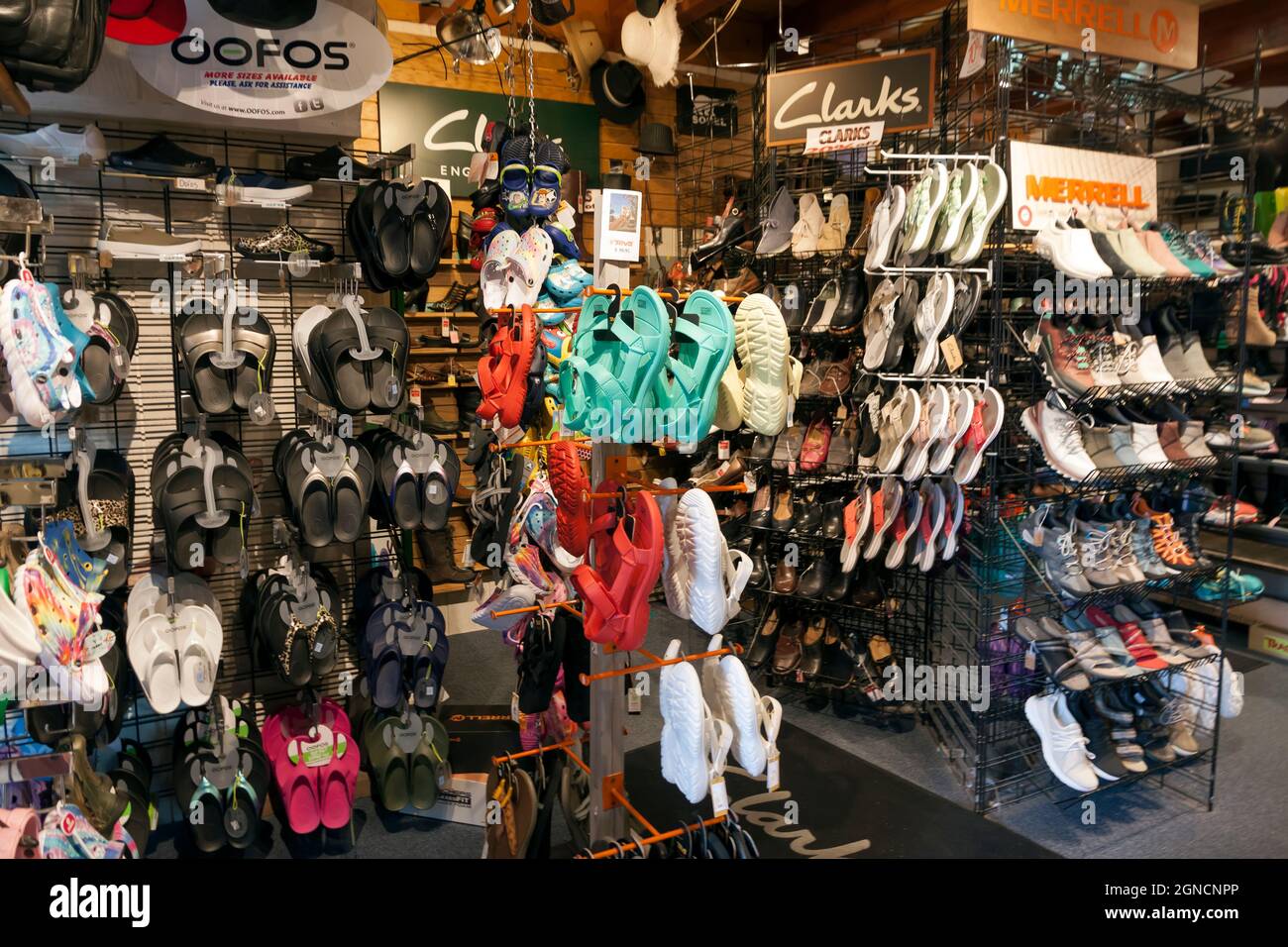Shoe store interior displaying sandals, shoes, and sneakers of various brands. Stock Photo